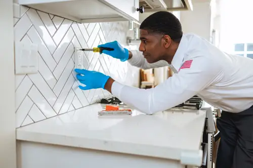 An Electrician Tech working on a buzzing outlet in a kitchen